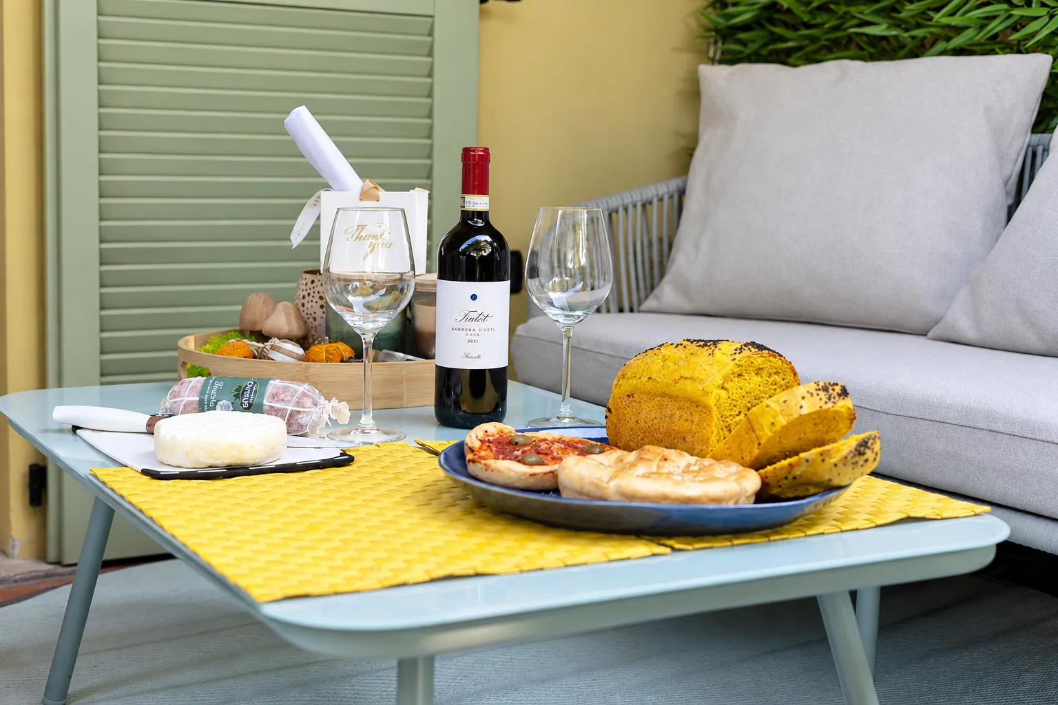 Der Willkommenskorb auf dem kleinen Tisch im Patio: Wein, Salami, Käse, Focaccia und etwas Süßes